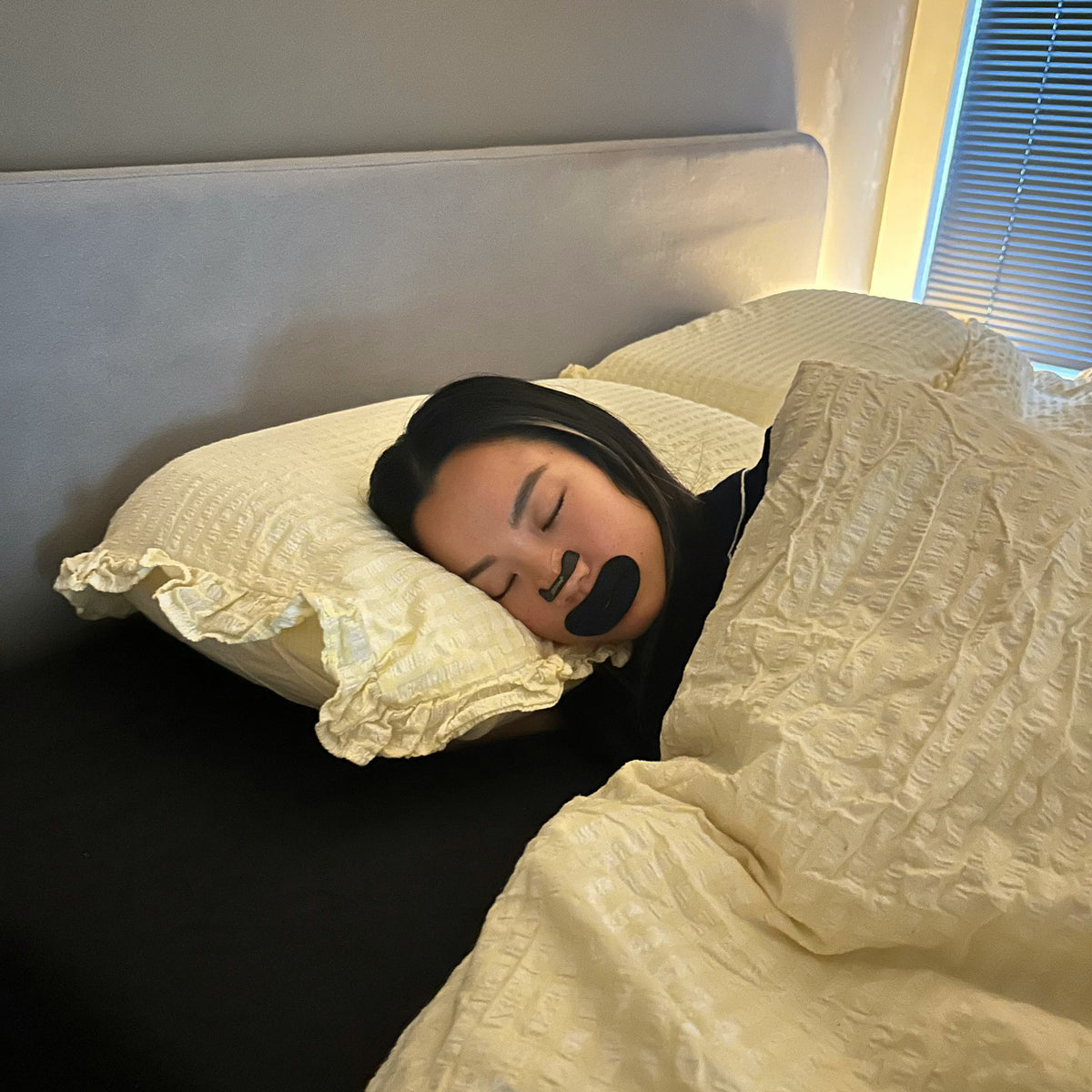 Man asleep on his side wearing an 18pointthree nasal strip and mouth tape