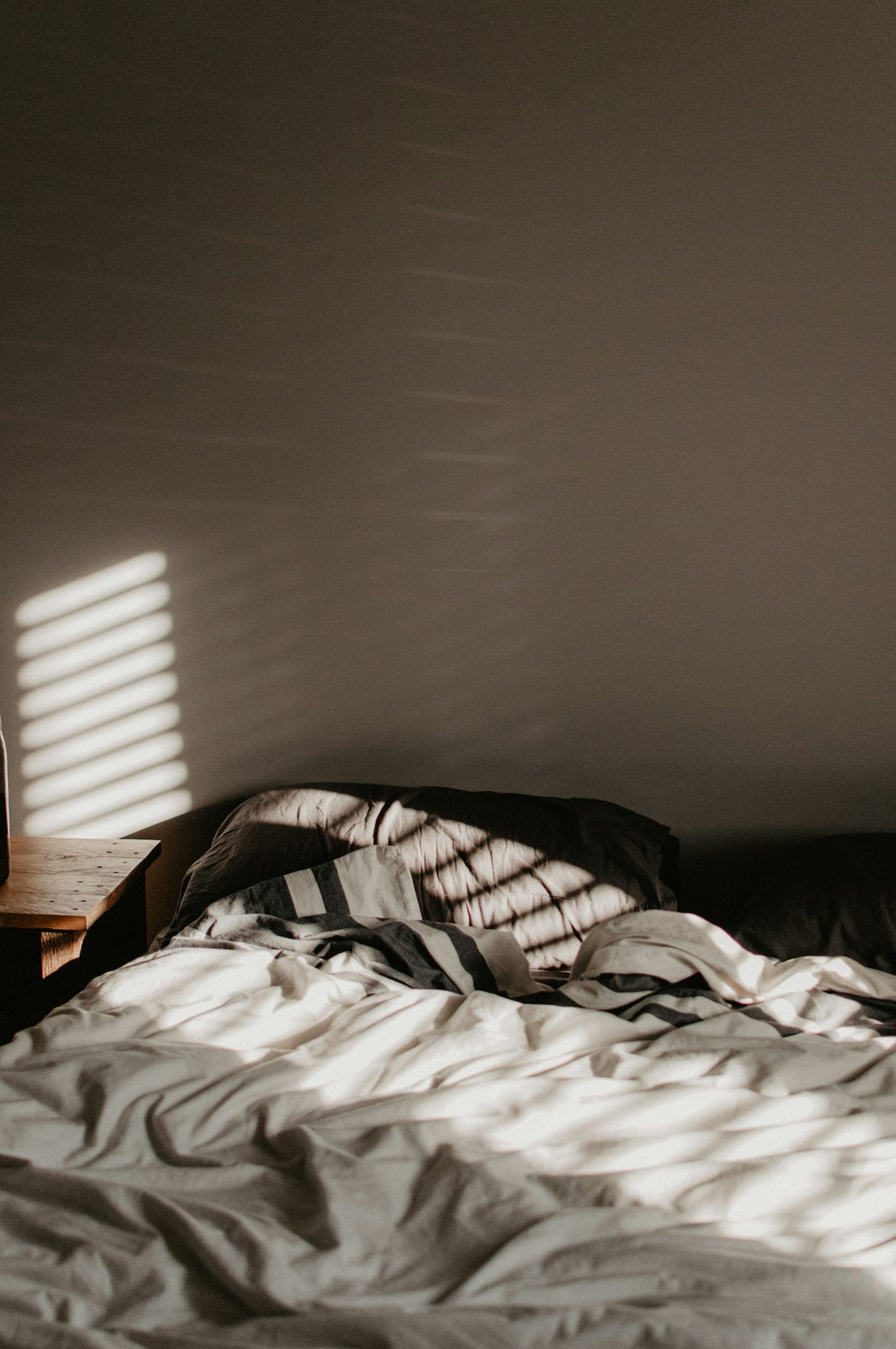 Cozy bed with warm morning sunlight streaming through the window on a winter morning