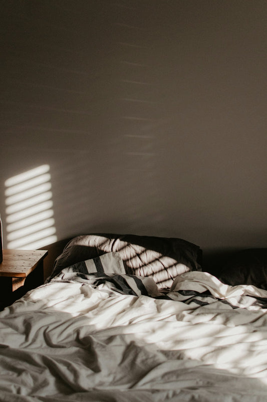 Cozy bed with warm morning sunlight streaming through the window on a winter morning