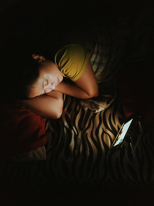 A person asleep on their side in soft light, head resting on a pillow