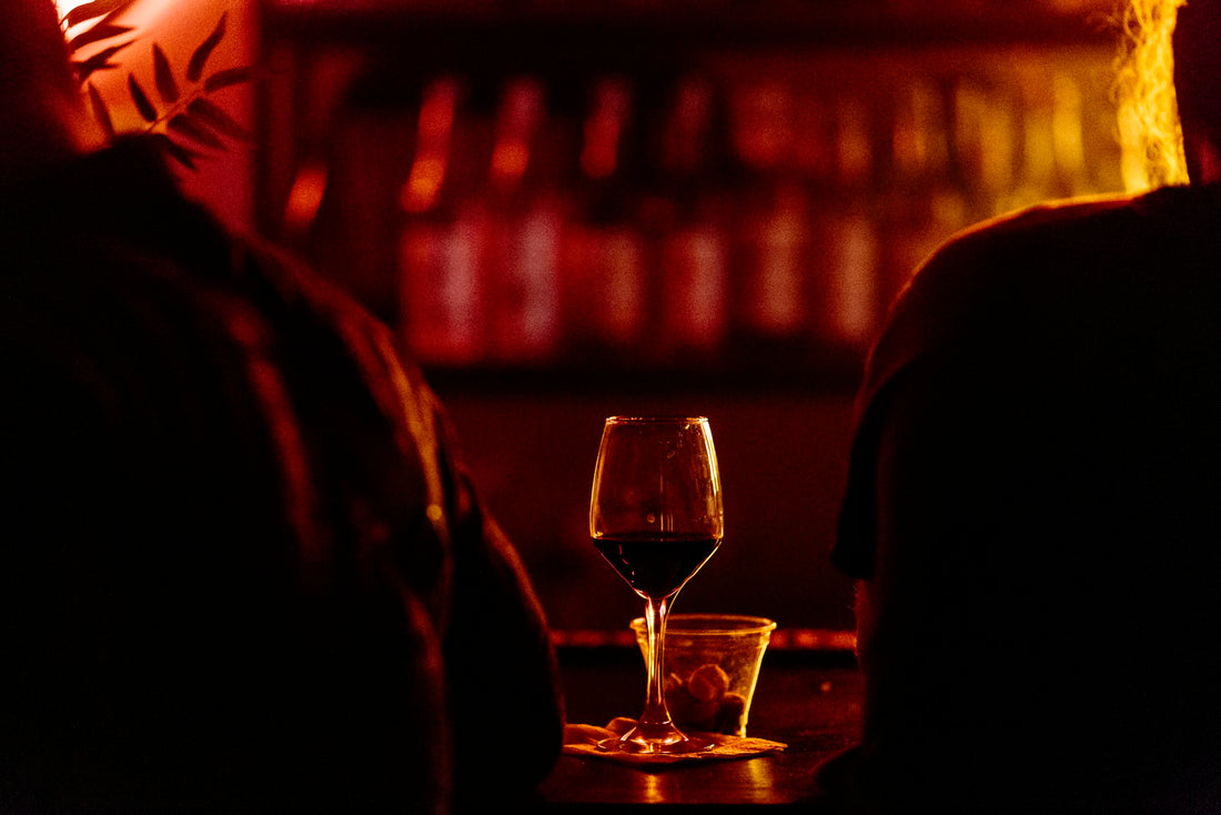 A near-empty wine glass in low, warm light at the end of the evening, suggesting a last drink before bed