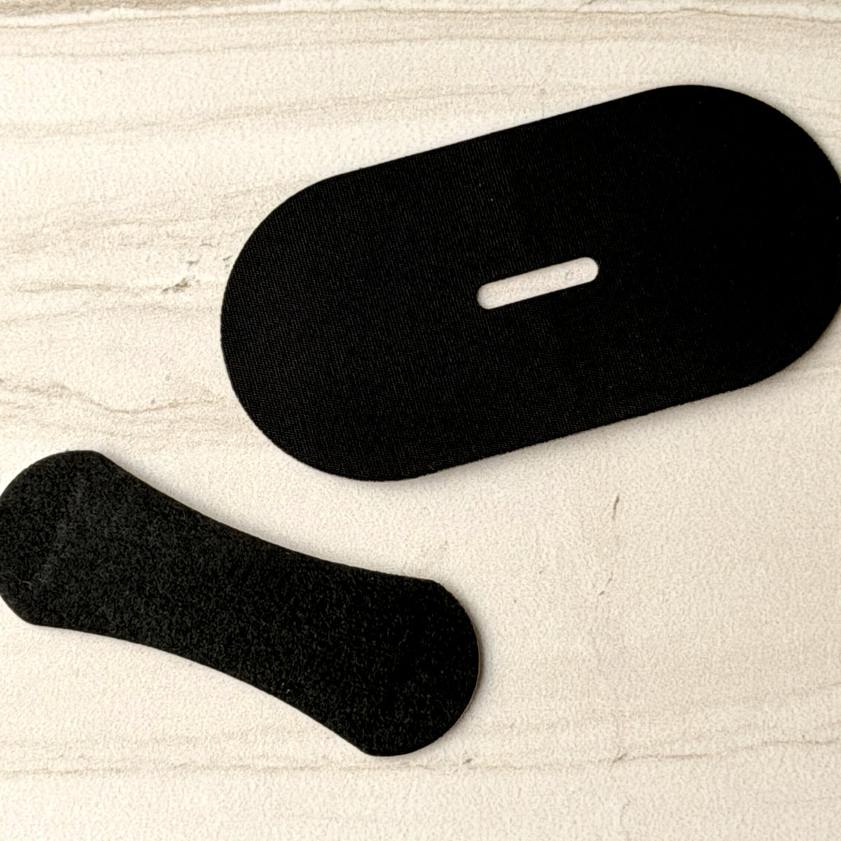 A piece of mouth tape and a nasal strip side by side on stone