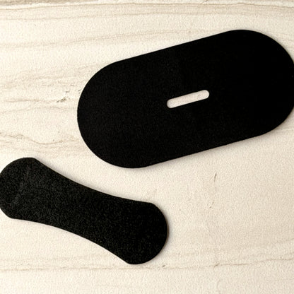 A piece of mouth tape and a nasal strip side by side on stone