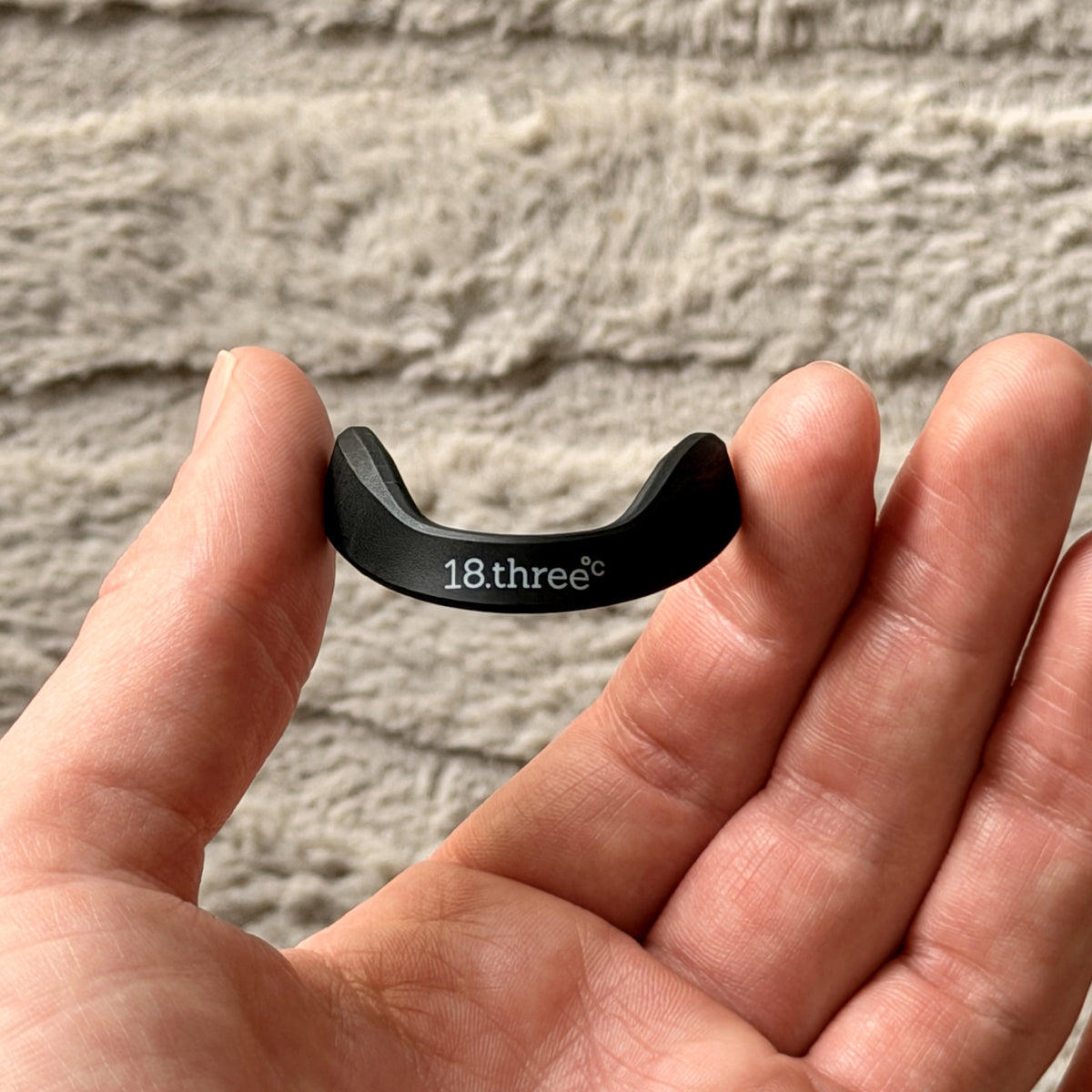 A magnetic nasal strip frame held in an open palm for scale