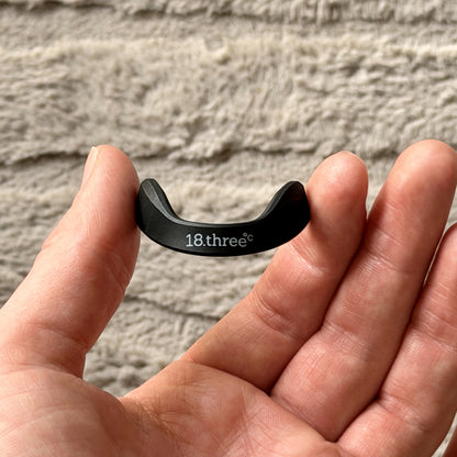 A magnetic nasal strip frame held in an open palm for scale
