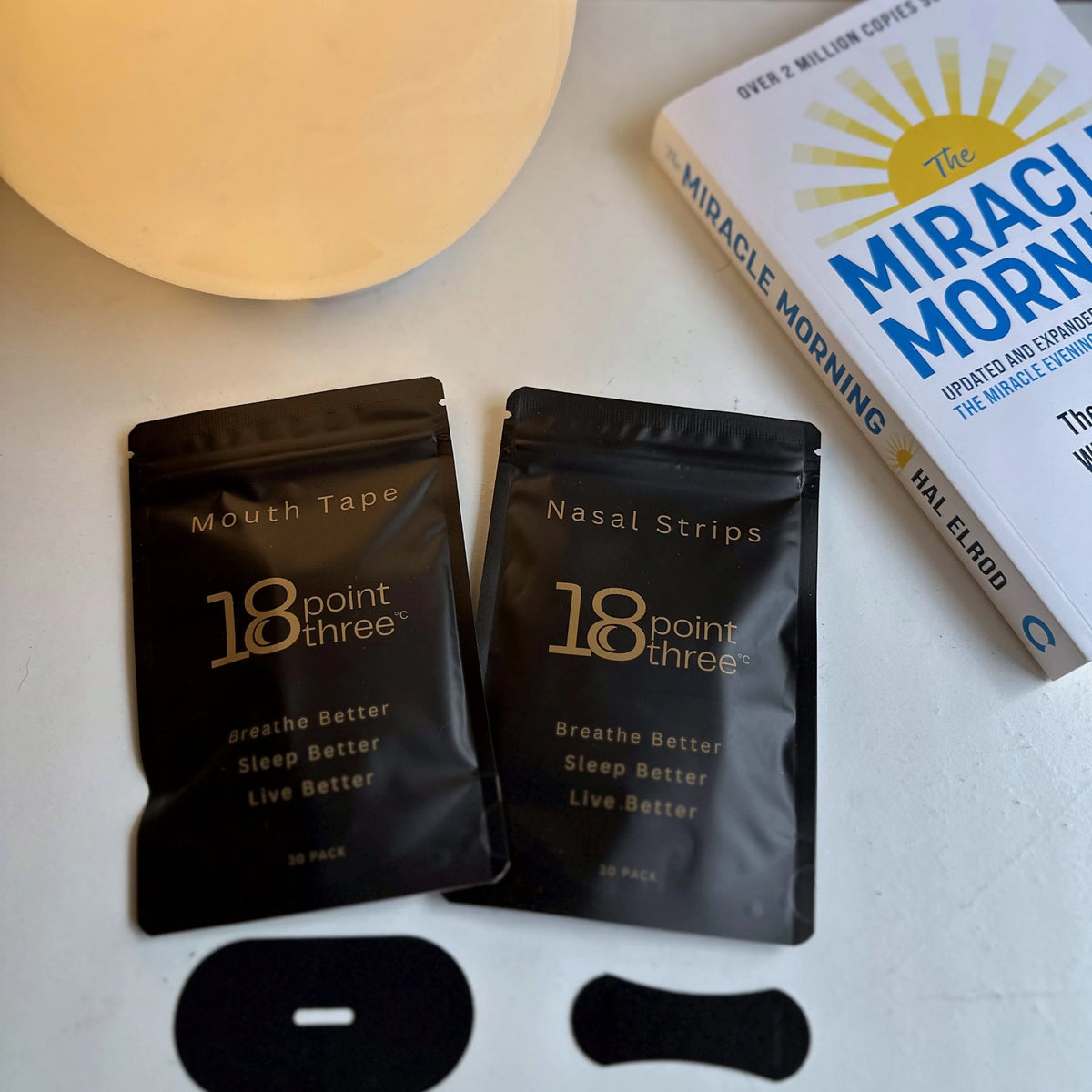 18pointthree Nasal Strips and Mouth Tape pouches on a bedside table