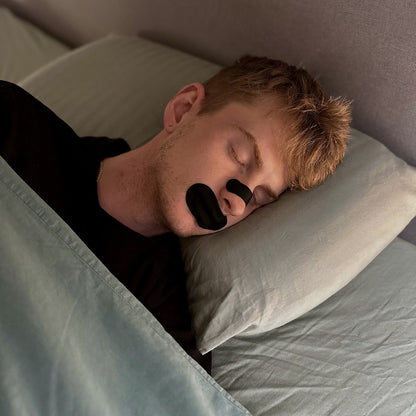 Man asleep wearing an 18pointthree nasal strip and mouth tape