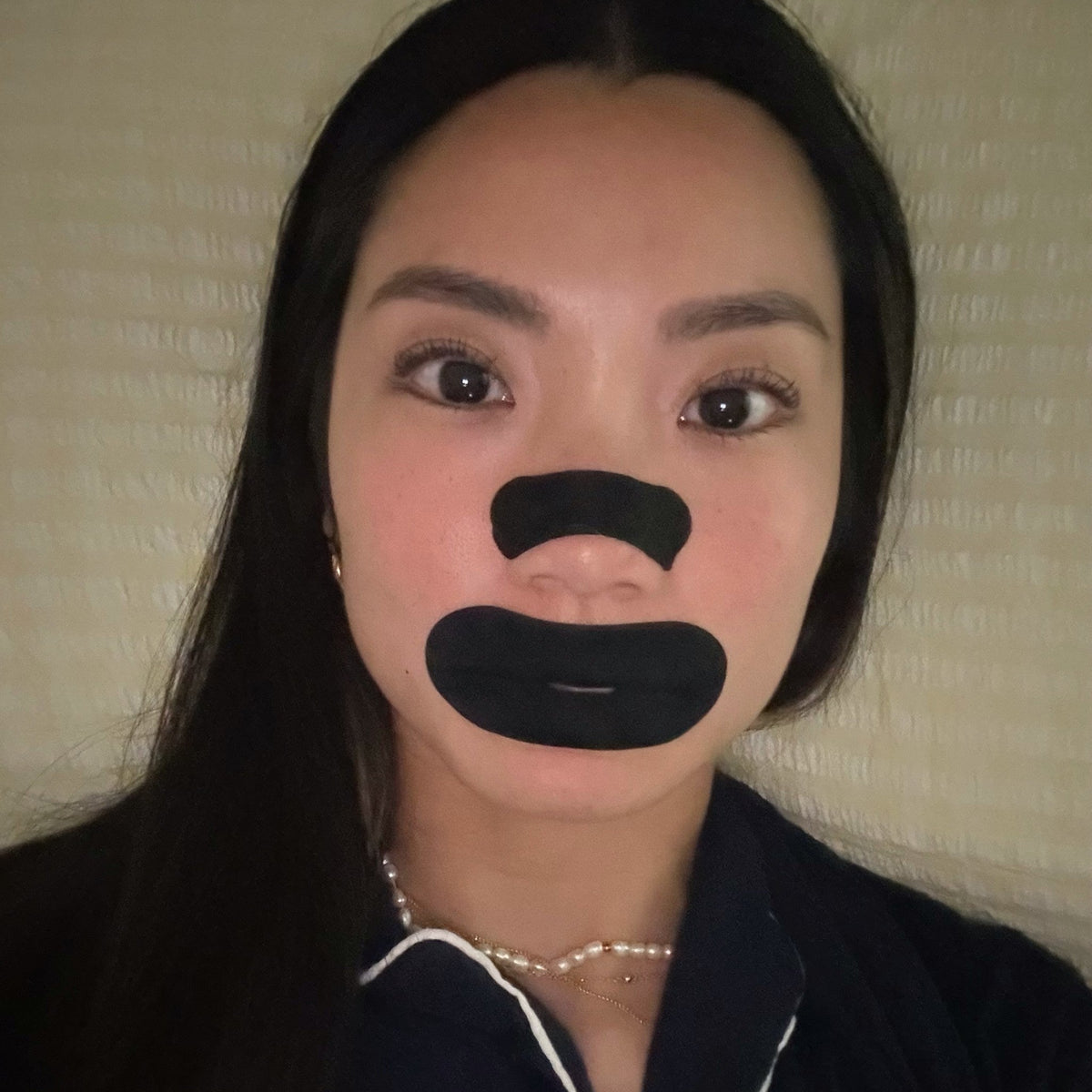 Woman in bed wearing an 18pointthree nasal strip and mouth tape